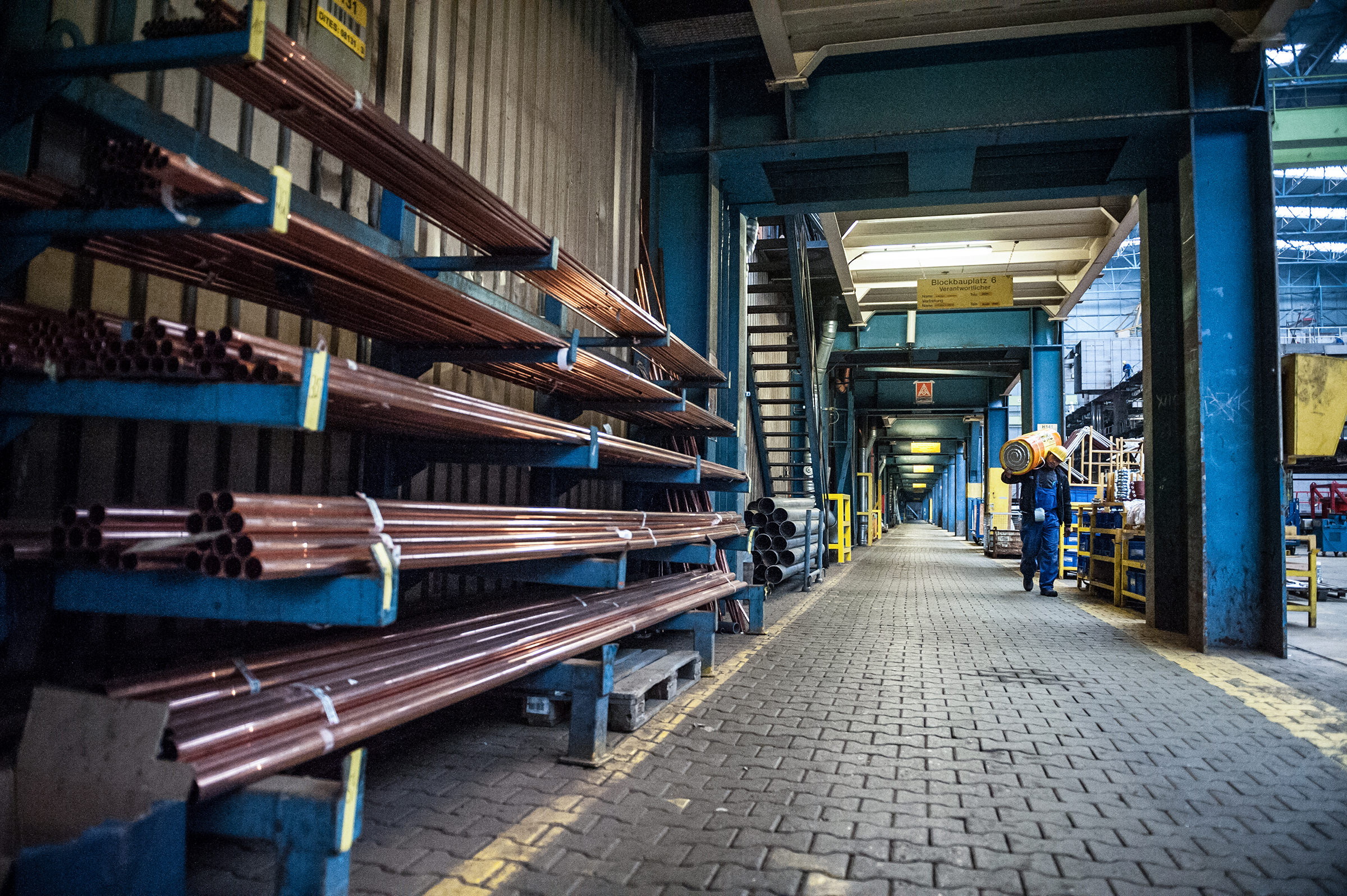 Ein Arbeiter der Meyer Werft geht durch eine Halle mit Isolationsmaterial auf der Schulter, Papenburg, Deutschland