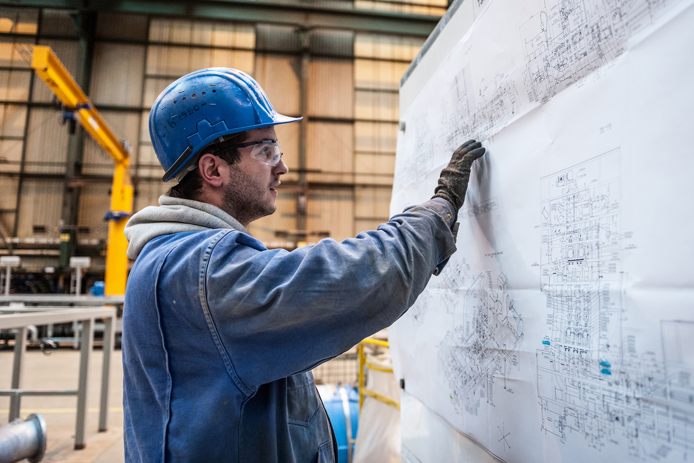Ein Arbeiter der Meyer Werft steht vor einer Skizze der Industrieanlagen in einer Halle, Papenburg, Deutschland