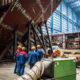Mitarbeiter der Meyer Werft stehen in einer Halle vor einem Schiff, welches repariert bzw. gebaut wird, Papenburg, Deutschland