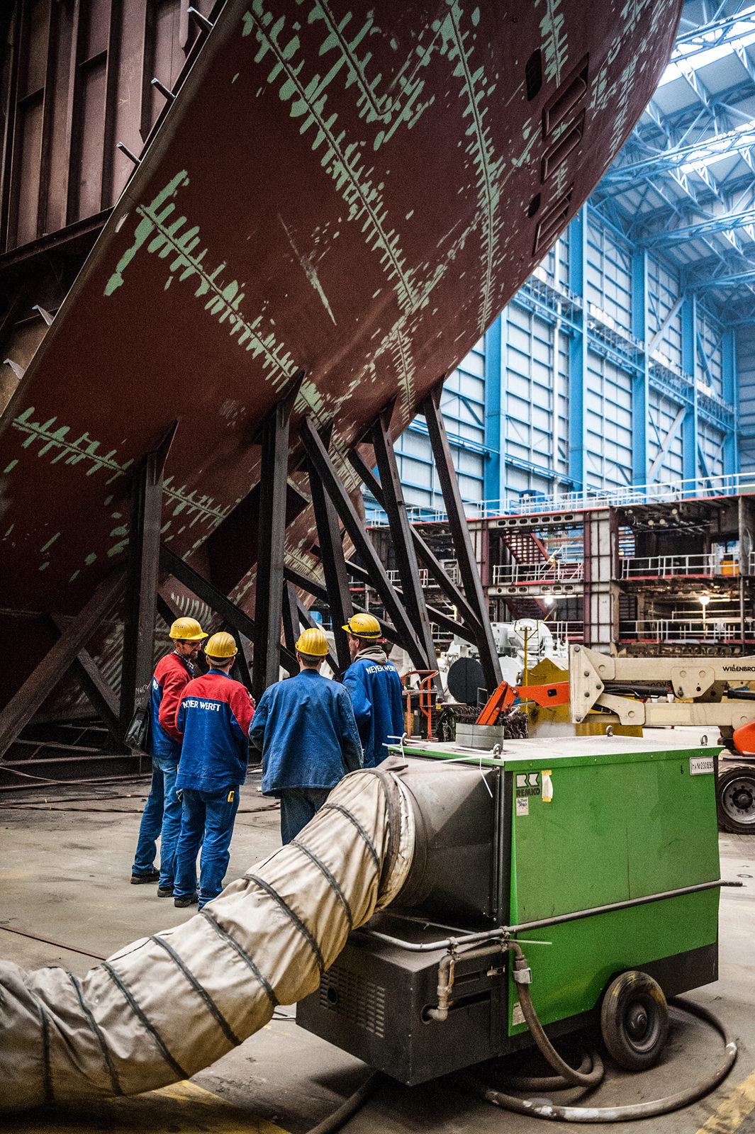Mitarbeiter der Meyer Werft stehen in einer Halle vor einem Schiff, welches repariert bzw. gebaut wird, Papenburg, Deutschland