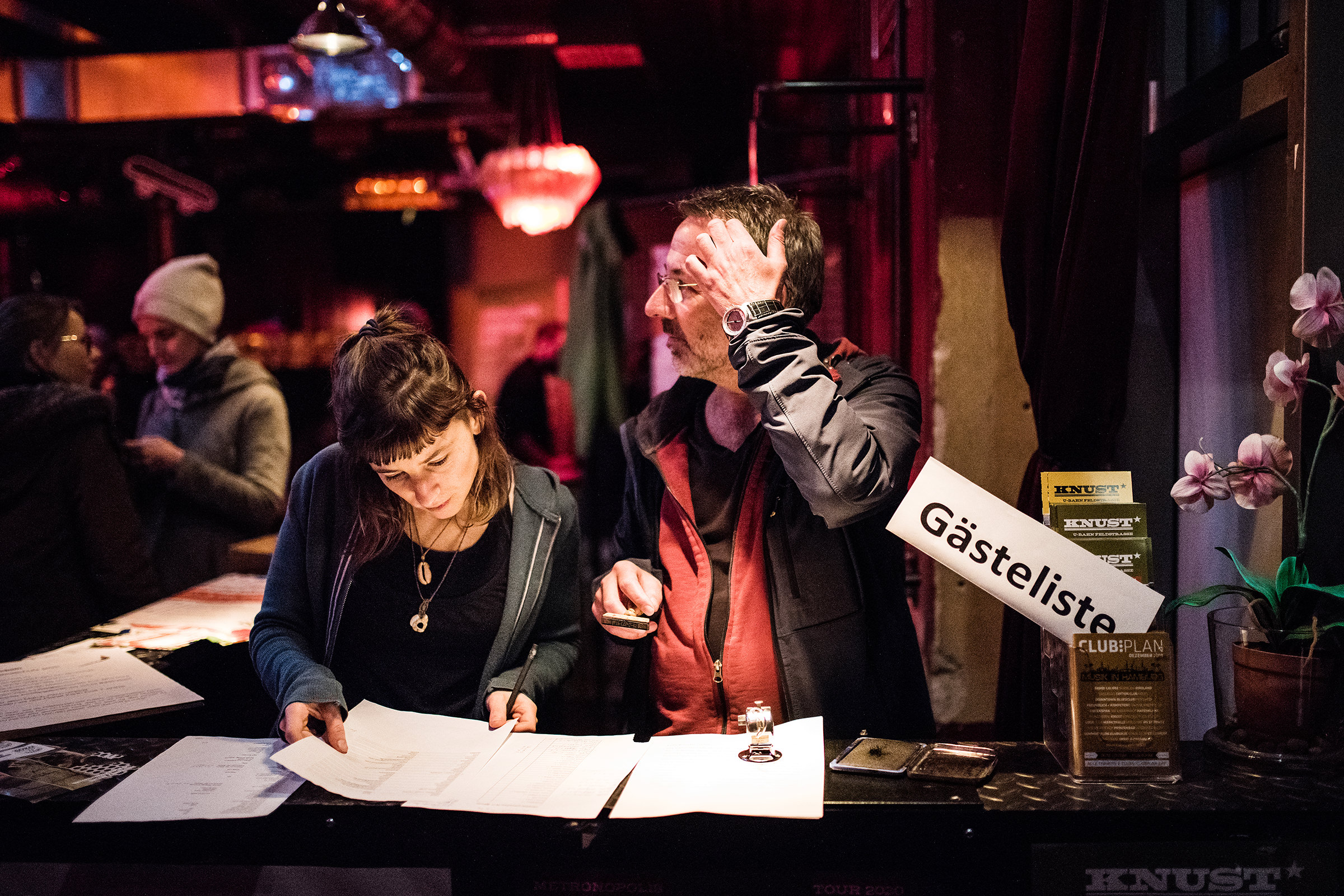 Ein Bild von einem Eventfotografen mit einem Mann und einer Frau, die Gäste am Eingang bei einem Konzert in Knust in Hamburg notieren