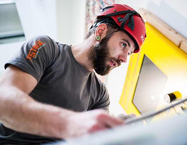 Fotoaufnahmen von Arbeitskräften im Produktionsprozess in Hamburg, Porträt eines Arbeiters mit Schutzhelm in der Fabrik