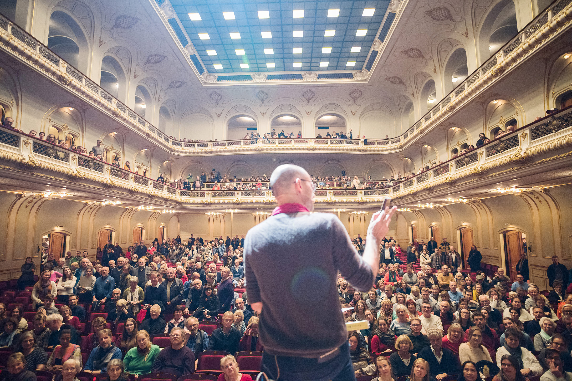 Ein Fotograf steht auf der Bühne vor dem Publikum in der Laeiszhalle im Rahmen einer Veranstaltung in Hamburg und trägt vor, fotografiert von einem Eventfotografen