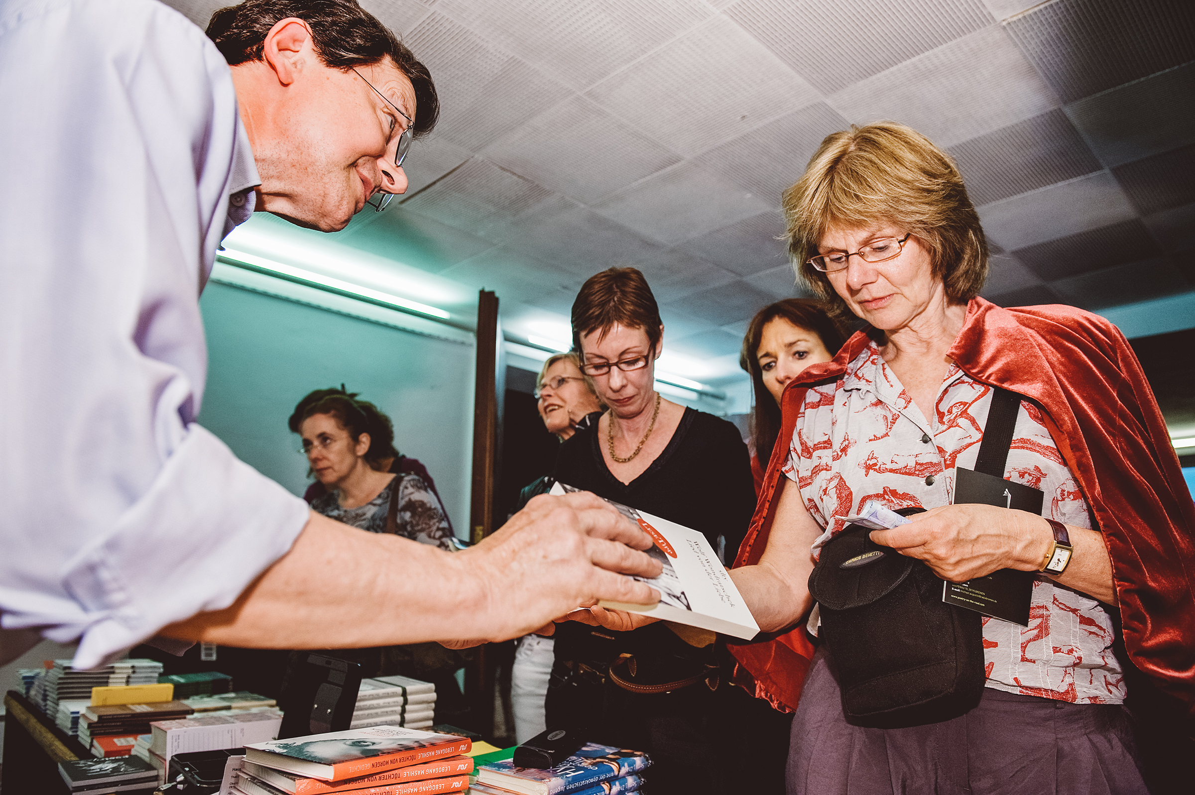 Eine Frau kauft ein Buch am Stand im Theaterfoyer im Rahmen des Internationalen Literaturfestivals Poetry On The Road in Bremen