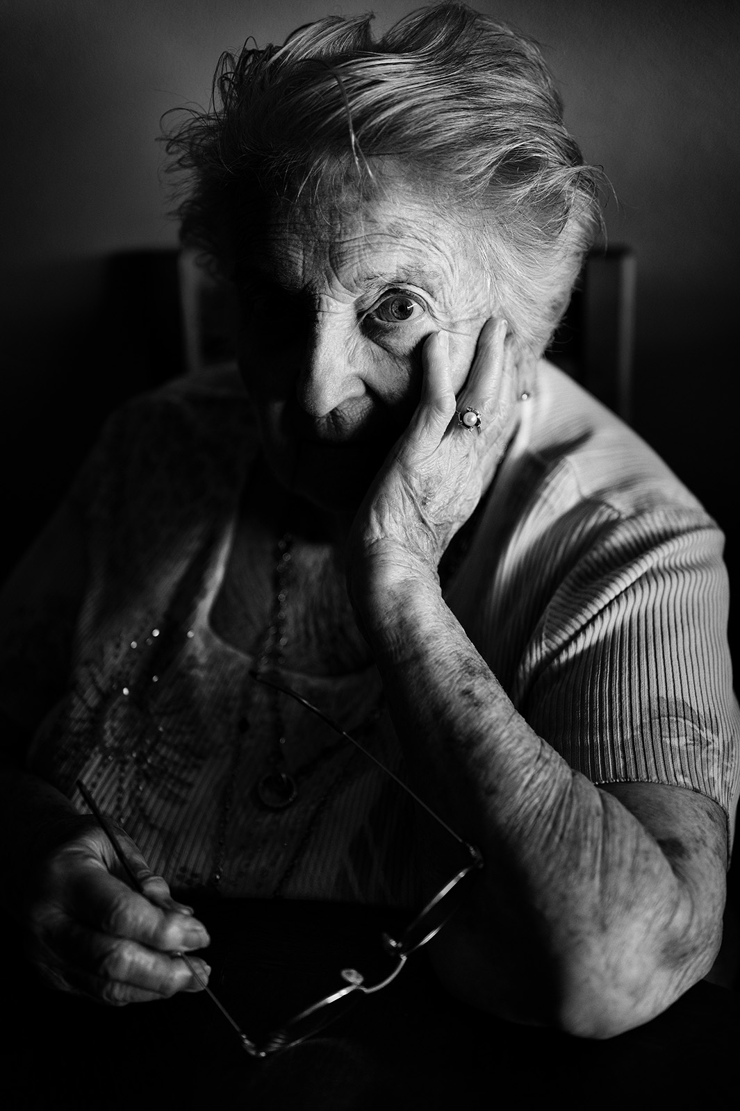 This evocative black and white documentary portrait of an elderly woman, her gaze holding a lifetime of family stories, exemplifies the art of authentic family photography.