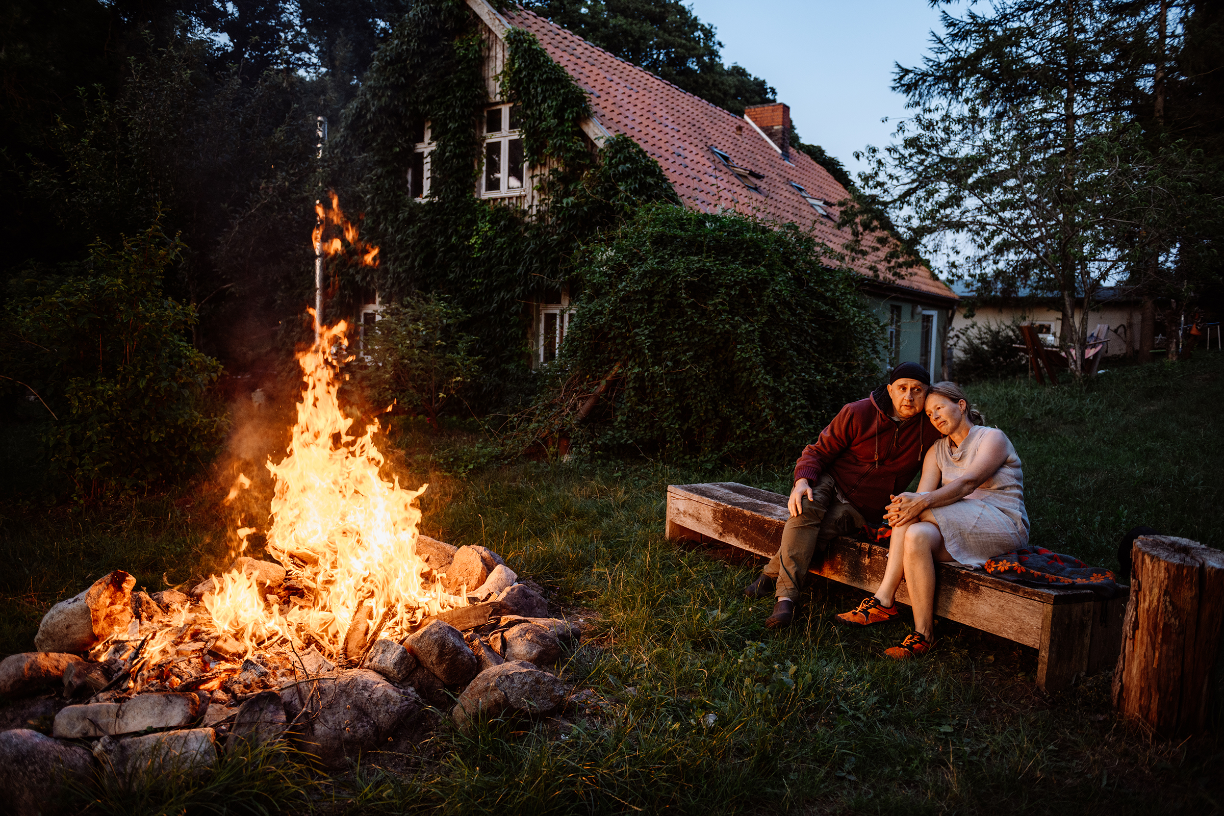 A couple enjoys a cozy evening by a bonfire in front of their home, creating a warm and intimate atmosphere.